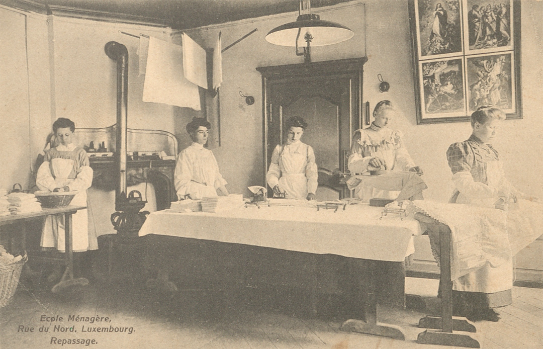Carte postale non datée et éditée par P. Fiedler à Luxembourg montrant des élèves de l’école ménagère lors d’un cours de repassage